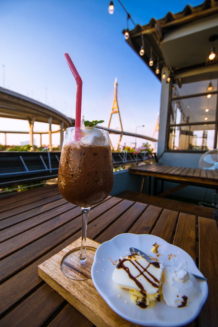 Delight in a refreshing iced drink and dessert at a rooftop cafe with a stunning cityscape view.
